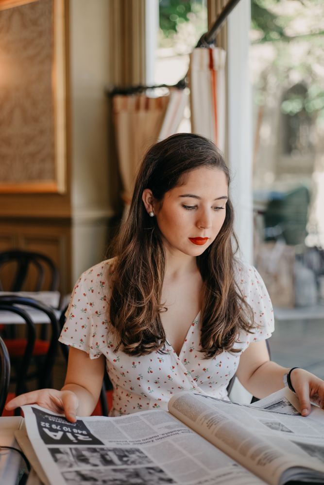 Woman reading a newspaper in a bright cafe