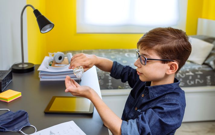 Teenager applying hand sanitizer before doing homework