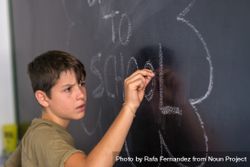 Boy writing on chalkboard bGpqv0