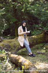 Middle Eastern woman relaxing with a book in the forest 5o9o1b