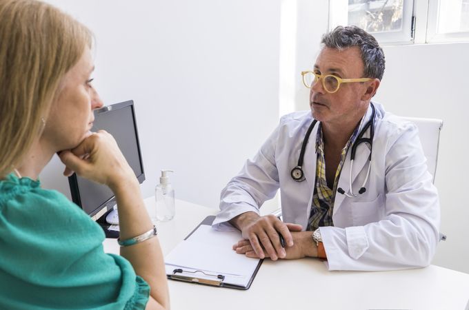 Male doctor telling his patient her diagnostic in his medical office