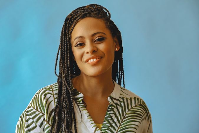 Portrait of shy smiling female with long braided hair in printed leaf shirt