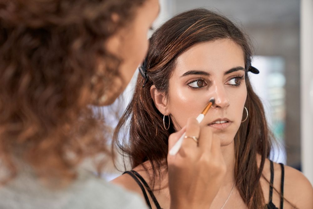 Faceless woman applying makeup on model