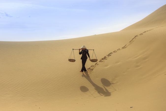 Person walking in desert holding balance on his shoulders