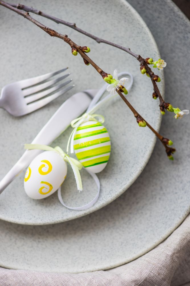 Top view of table setting for Easter dinner with egg ornaments and branch
