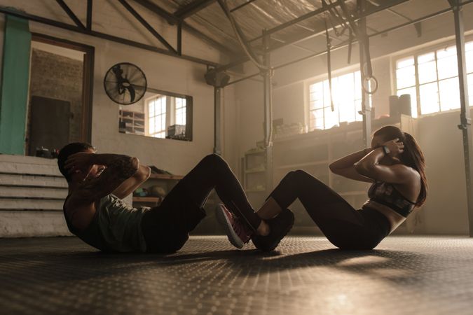 Couple doing sit-ups together in gym