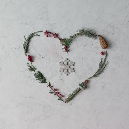 Heart shape made of winter foliage with snowflake