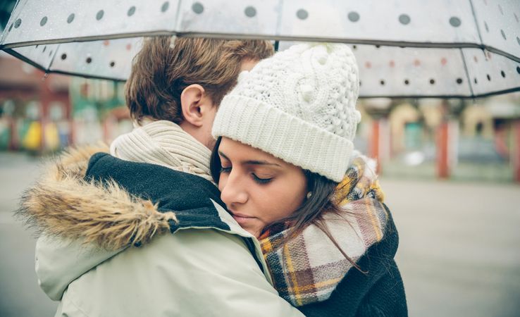 Couple embracing each other under the umbrella on an autumn rainy day