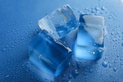 Close up shot looking down at top view of four melting ice cubed on blue table
