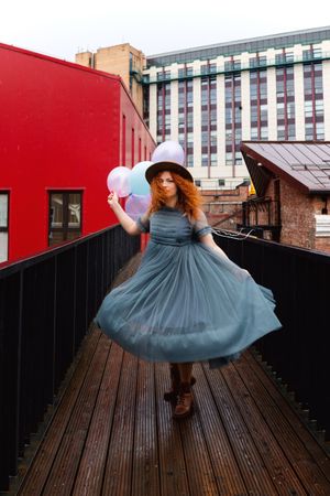 Woman twirling in streets with balloons