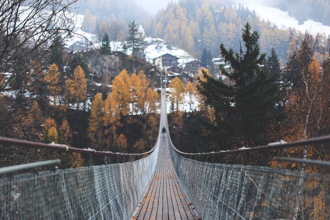 Person walking on suspension bridge in mountain town