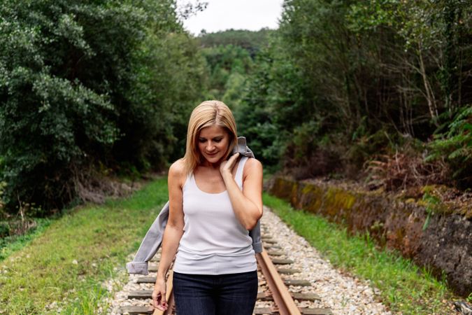 Woman walking along railway though greenery part of road