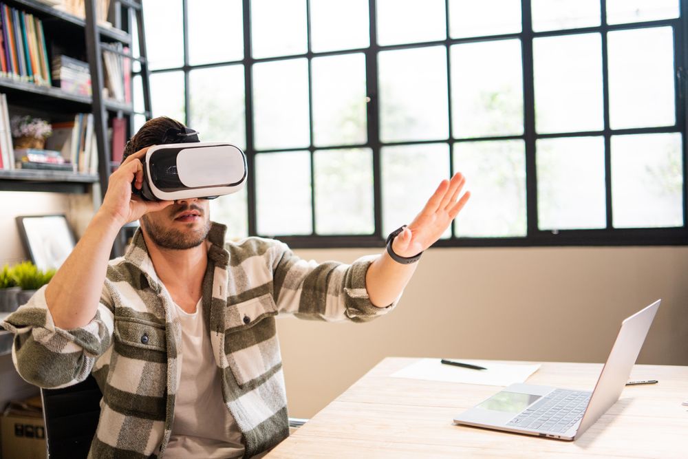 Male in bright modern office with arms up in VR headset