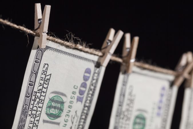 Hundred Dollar Bills Hanging From Clothesline on Dark Background