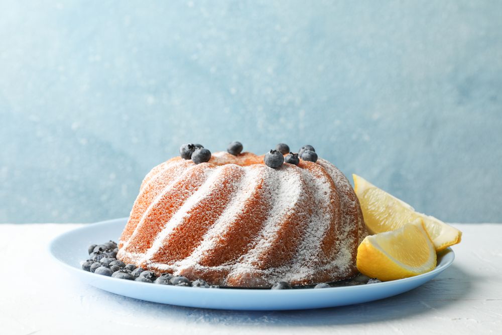 Cake with powder sugar and blueberry on blue background, space for text
