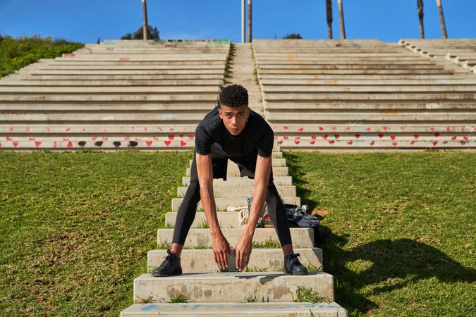 Fit Hispanic man warming up on stairs