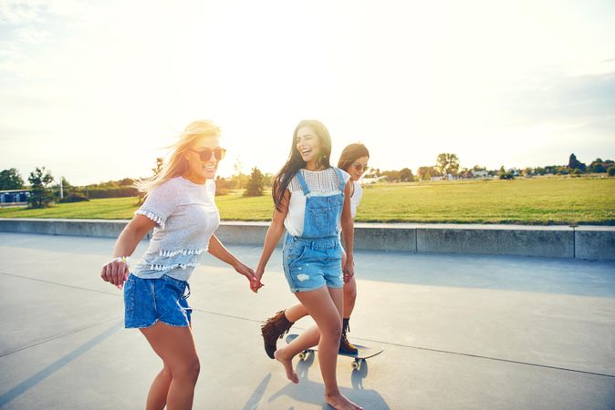 Happy female friends skateboarding on boardwalk