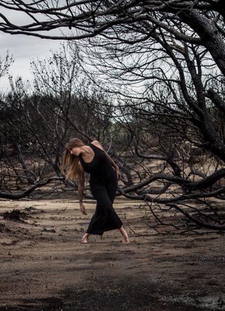Woman dancing between dry trees