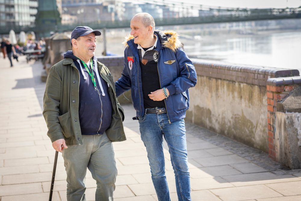 Two male friends walking by the river and having a conversation