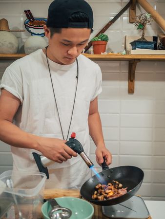 Asian male cooking in kitchen