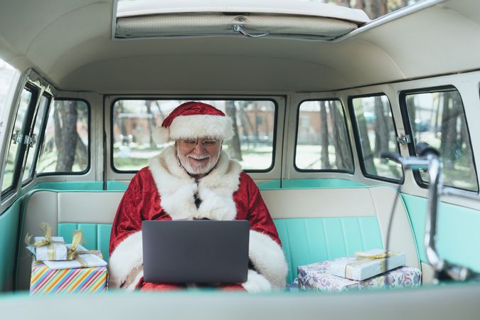 Santa Claus working at laptop in van