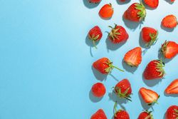 Flat lay composition with strawberries on color background, space for text. Summer sweet fruits and berries