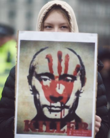London, England, United Kingdom - March 5 2022: Woman holding sign of Putin’s face with red hand
