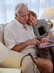 Mature man browsing tablet with grandson