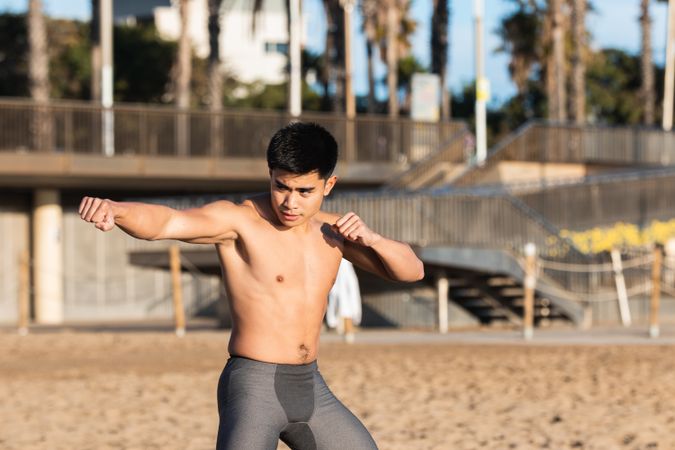Athletic man in boxing stance training on beach
