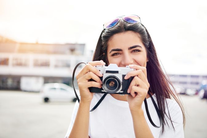 Happy woman taking pictured with camera to her face