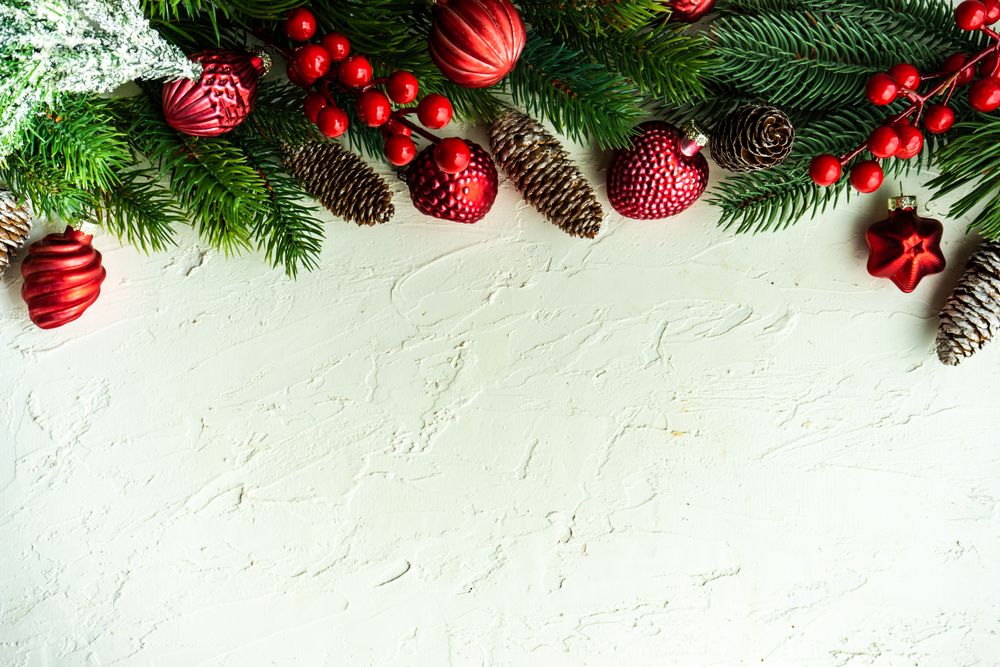 Wintry pine branch, ornaments and holly berries on top of horizontal frame