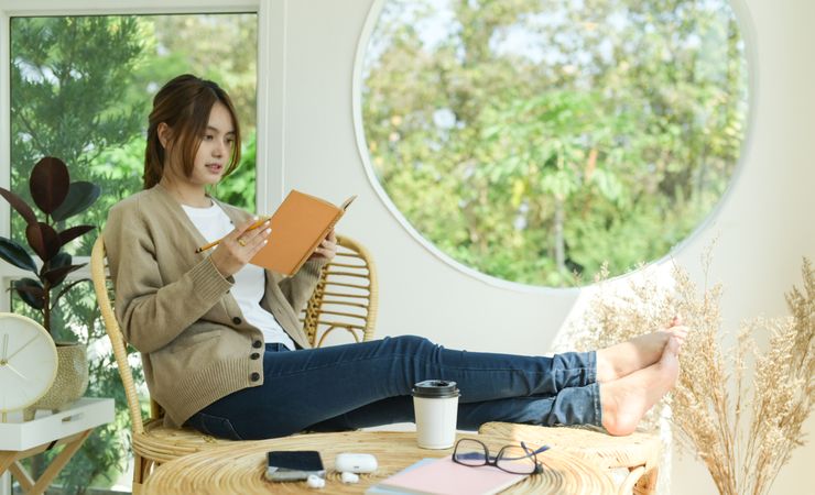 A beautiful woman reading a book in the living room at home