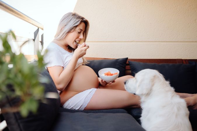 Smiling pregnant woman chilling with dog