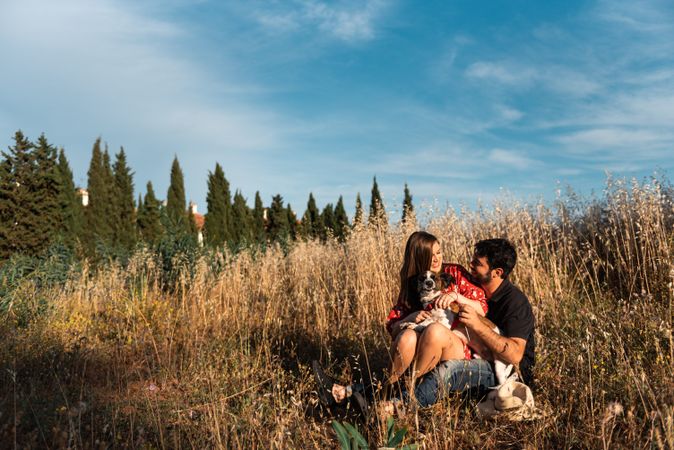 Happy couple with friendly cute dog resting outdoors