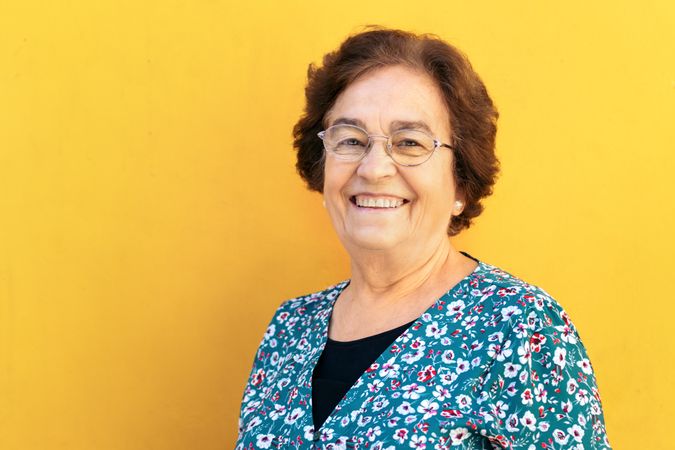 Cheerful older woman on yellow background
