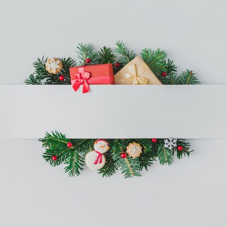Christmas tree branches with decorations and cookies, behind gray paper