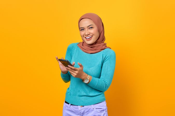 Happy Muslim woman holding her smartphone