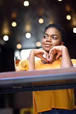 Female sitting with ice tea at counter of modern cafe