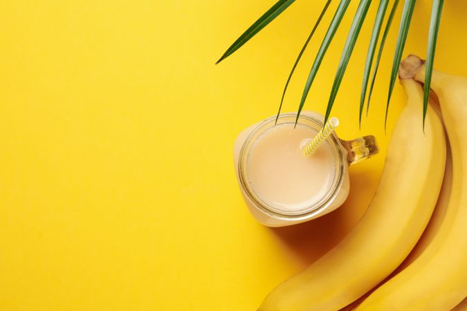 Bananas and juice on yellow background. Fresh fruit