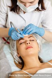 Woman having facial beauty treatment with instrument above her eyebrows, vertical 5Rxd2b