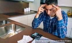Stressed man with calculator and bills in kitchen 4MVDkb
