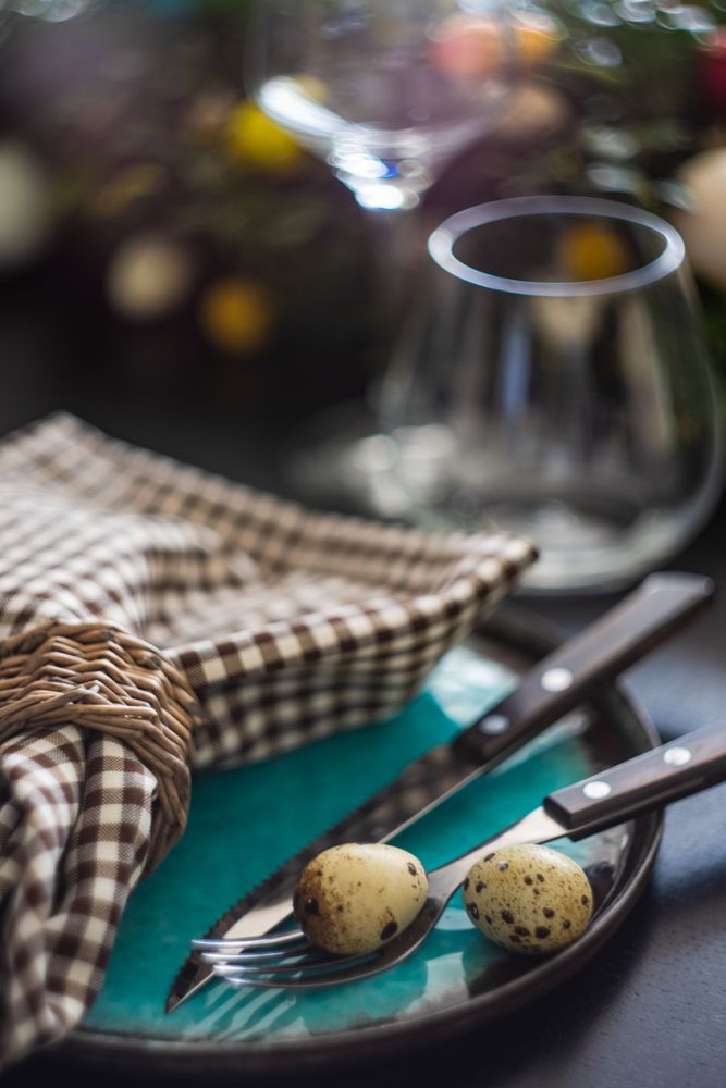 Close up of Easter table setting with delicate spotted eggs on ceramic teal plate