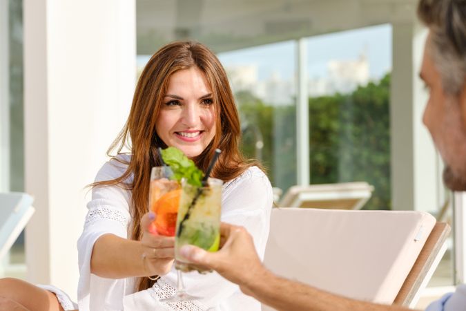 Smiling couple toasting with summer cocktails on terrace of hote