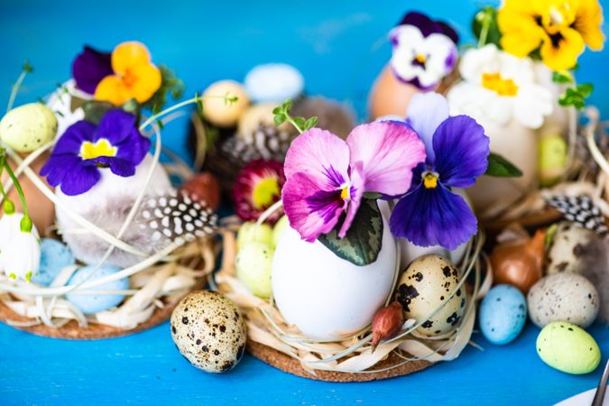 Easter holiday card concept with eggs and flowers on bright blue table