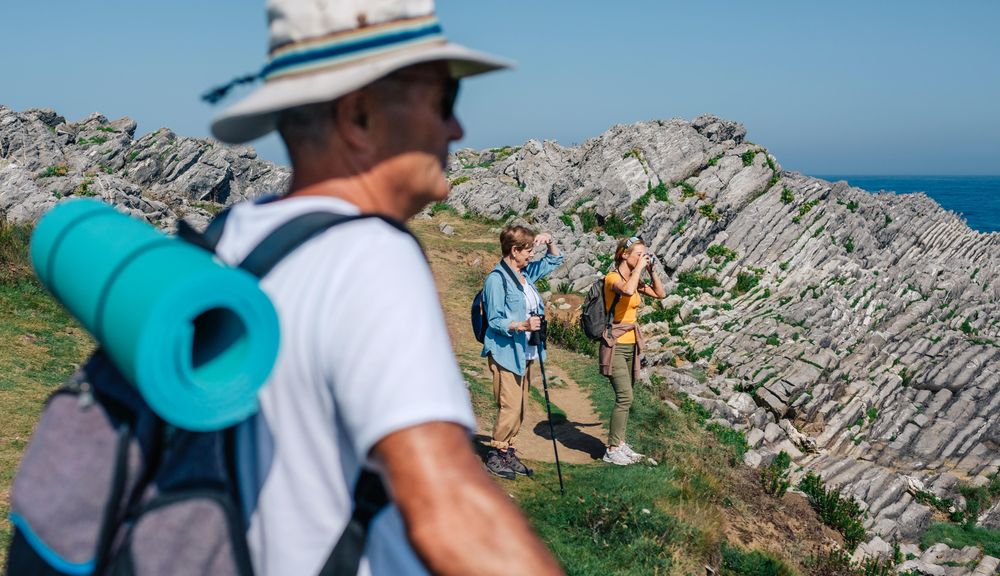 Man in foreground of his family taking photos of the view while hiking