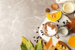 Composition with glass cup of pumpkin latte on gray background