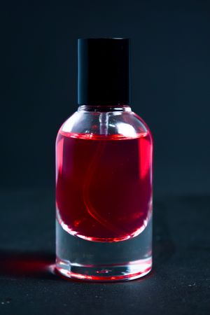 Red perfume bottle in dark studio with copy space