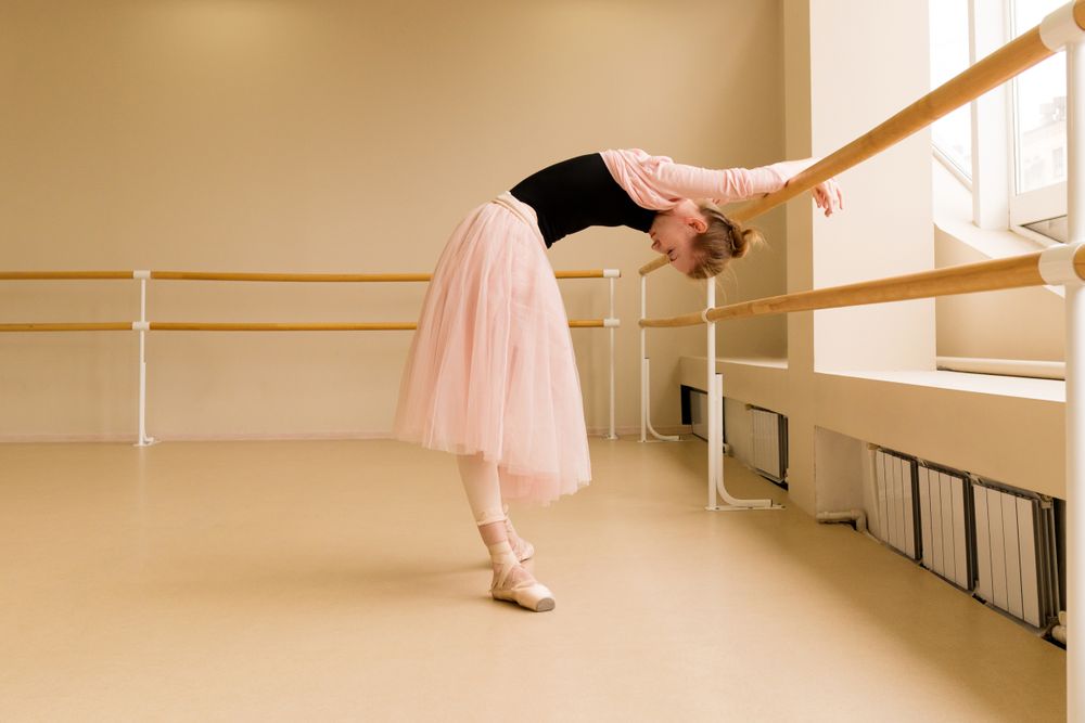 Ballet dancer arching backward at barre