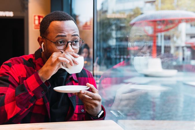 Black man with cup of coffee in cafe