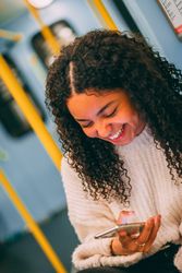 Smiling Black woman using smartphone in transport
